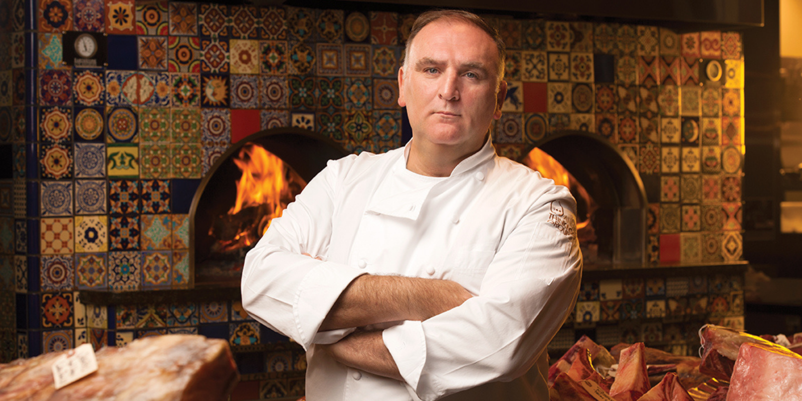 Jose Andres standing in from of flame ovens surrounded by meat