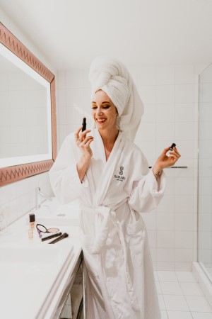 Female in a bathrobe and towel on her head putting make up on in the bathroom