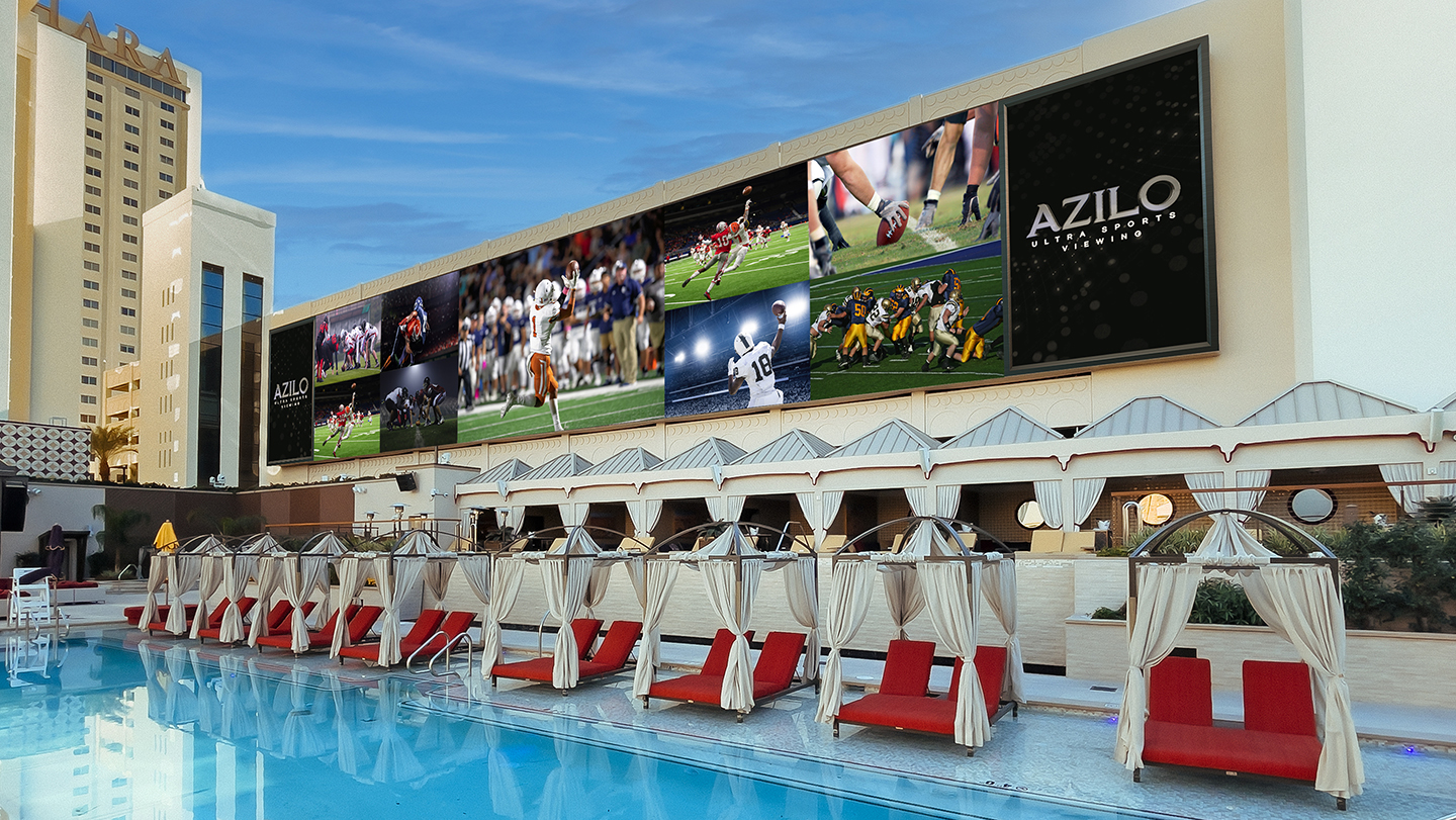 View of the Azilo Ultra Pool. Red and White cabanas under a very large screen that shows sports games. People can watch multiple games at the same time while lounging or swimming at Alizo Ultra Pool.