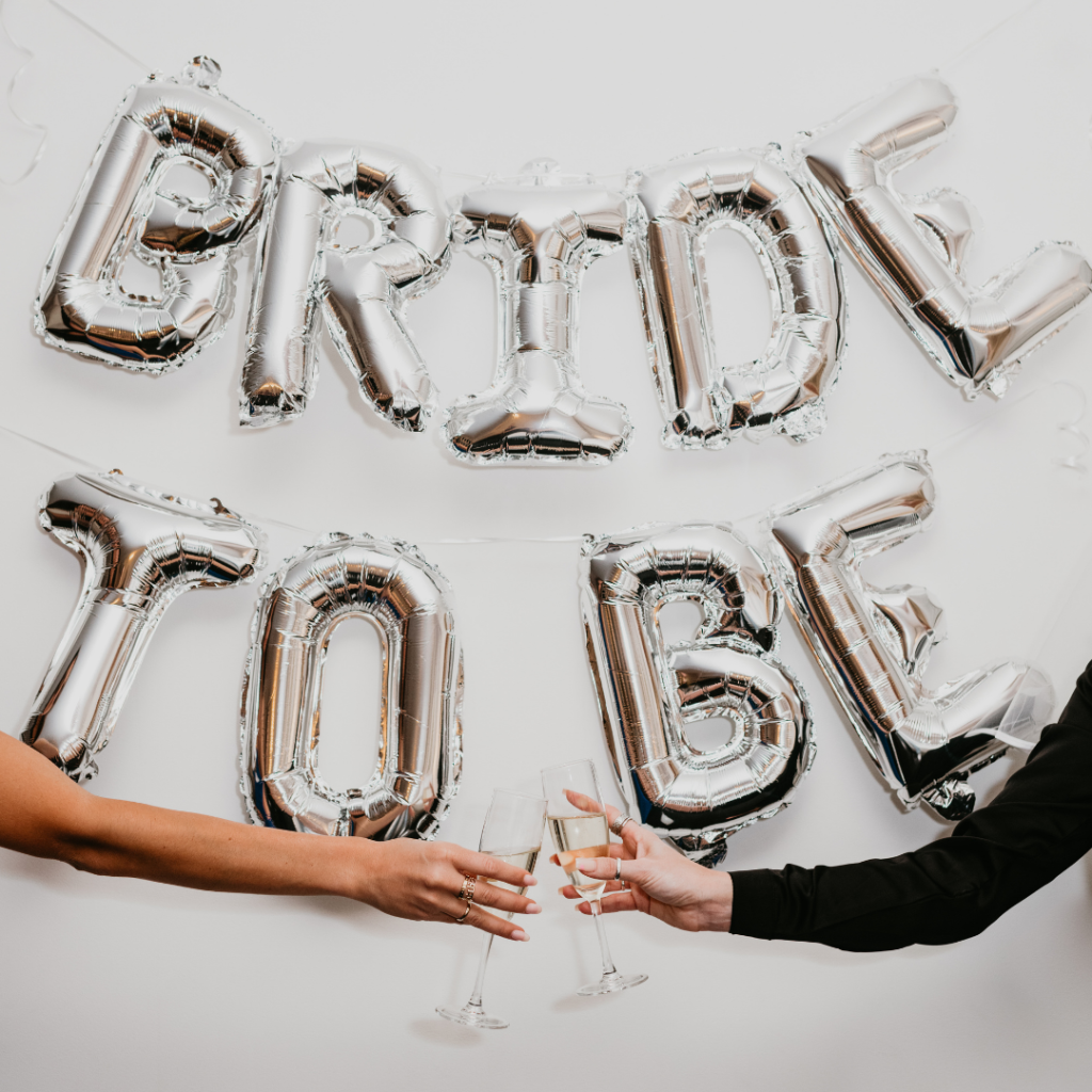 Bride To Be balloons hanging on a wall. Girls cheers with champagne