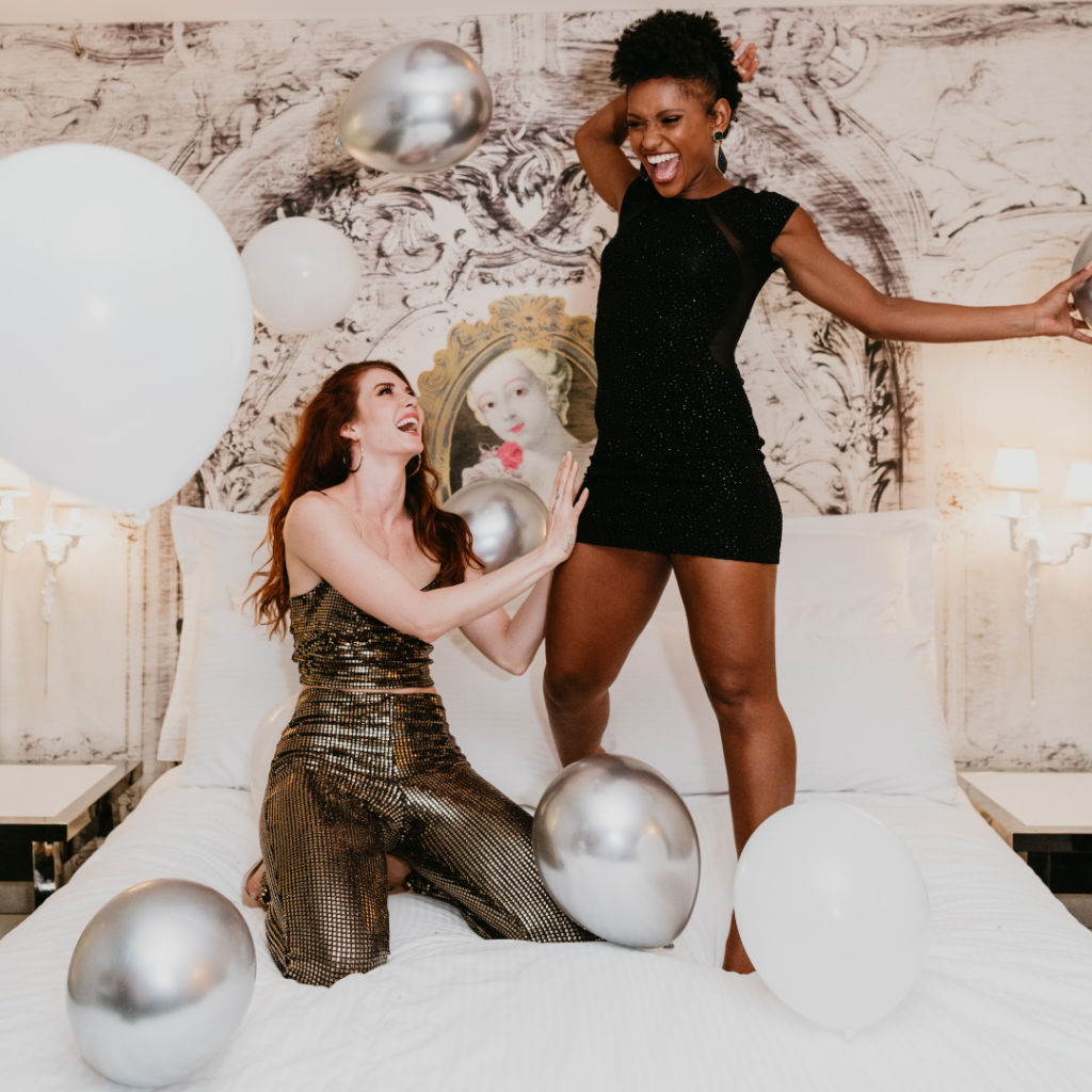 two girls playing on top of the bed with balloons