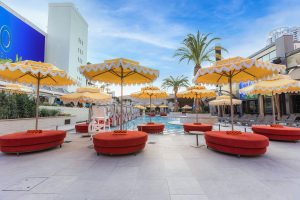 Daybeds with dark orange cushions facing a resort swimming pool