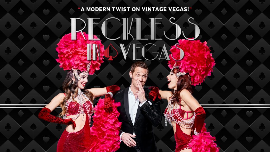 Gentleman in a tux with Vegas showgirls to his left and right