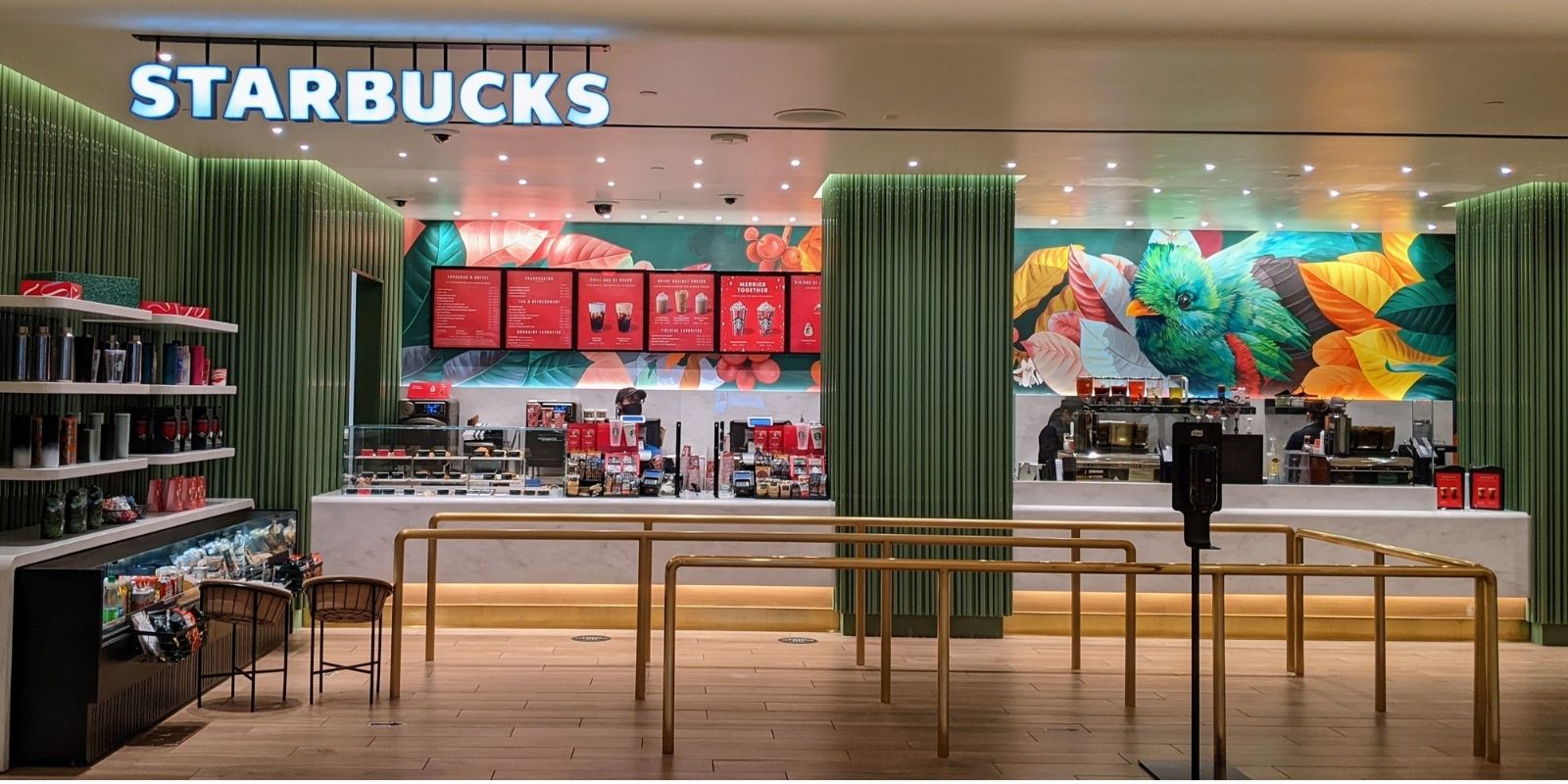 A picture of our Starbucks location. There is a beautiful hand painted mural on the back wall showing leaves and a teal colored bird. This is an architectural shot of the overall location.