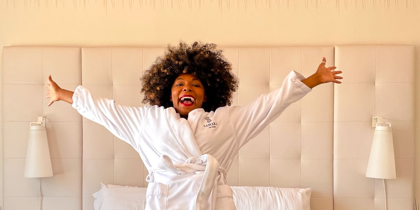 guest falling backward onto hotel bed with a big smile on her face