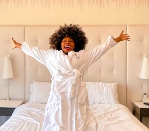 guest falling backward onto hotel bed with a big smile on her face