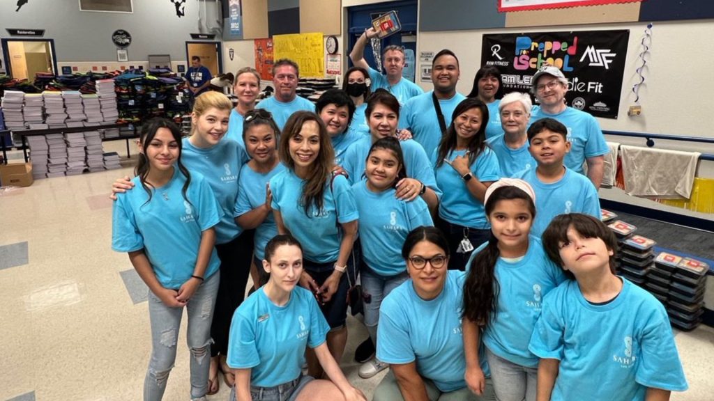 Team Members stuffing grade school backpacks for students. Group shot showing volunteers.