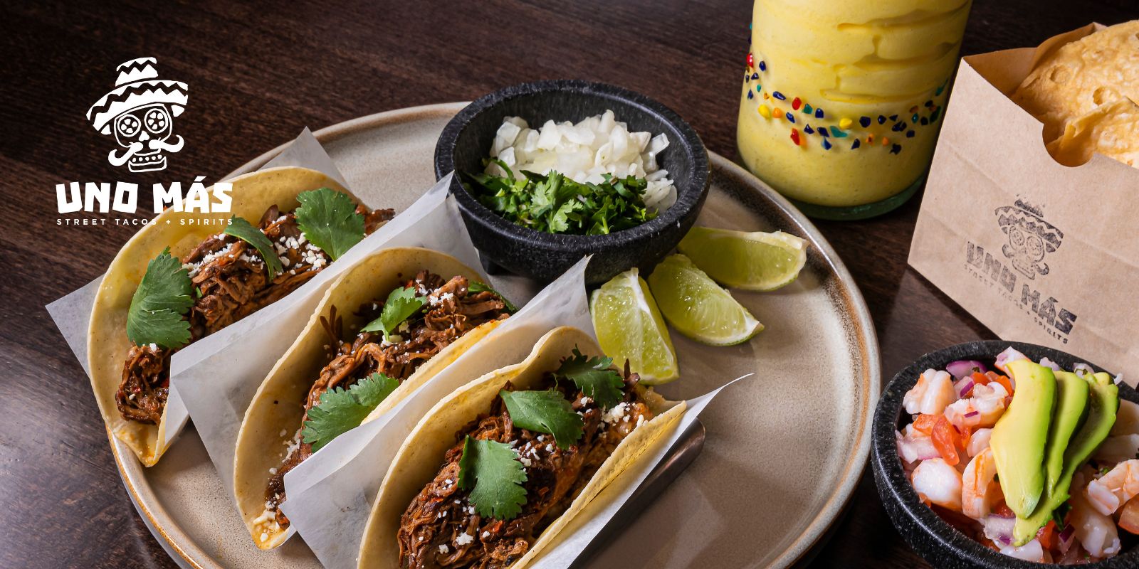 Uno Mas tacos and chips on a table with a drink